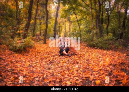 Una donna con il suo cane rosso Corgi Pembroke in una foresta autunnale o in un parco che si gode una passeggiata. Foto Stock