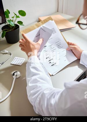 Professionista medico maschile che passa attraverso i documenti del paziente in un ospedale Foto Stock