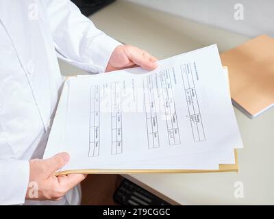 Professionista medico maschile che passa attraverso i documenti del paziente in un ospedale Foto Stock