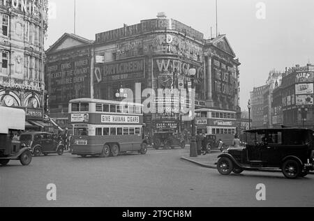 1938, storico, Piccadilly Circus in quest'epoca, mostra l'incrocio stradale e i veicoli del giorno, tra cui un London taxi e autobus a due piani. Sul lato di un autobus una pubblicità per i sigari dell'Avana e una per i Maclean, con Reginald Foort, un organista teatrale e una popolare emittente della BBC degli anni '1930 e '40 Foto Stock