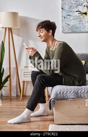 influencer transgender allegro e riccamente con smartphone e seduti a letto, social media Foto Stock