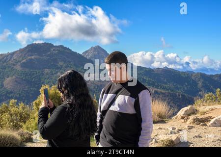 ragazzi latini, che scattano foto da smartphone delle montagne della sierra nevada, granada, spagna. Foto Stock