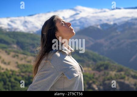 Escursionista che sembra molto felice di godersi il paesaggio mentre cammina all'aperto in inverno, Foto Stock