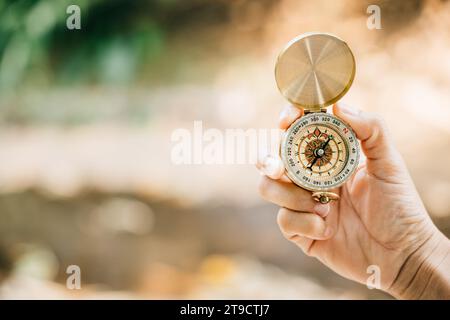 In mezzo alla pittoresca foresta e al tranquillo lago, una mano di donna tiene saldamente una bussola che incarna Foto Stock