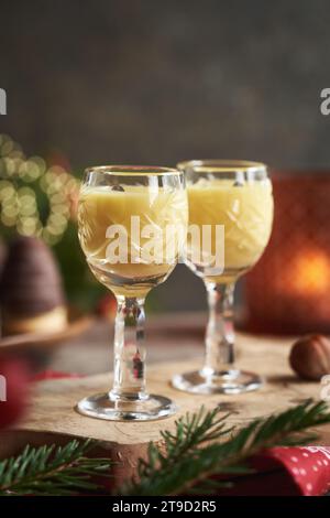 Due bicchieri di eggnog con biscotti di Natale e rami d'albero sullo sfondo Foto Stock