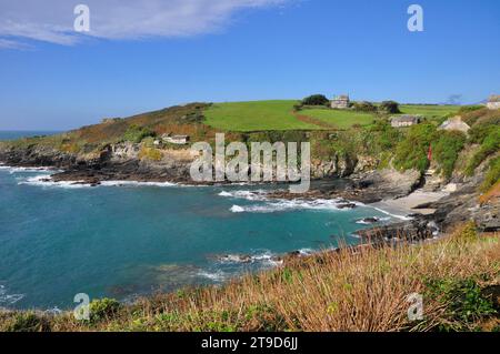 Il sole autunnale illumina la baia prussiana vicino a Marizion in Cornovaglia. Capanne dei pescatori in cima a una ripida rampa di accesso al piccolo lancio a riparato Foto Stock