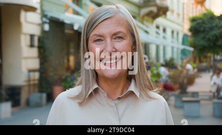 Ritratto ravvicinato felice anziano maturo dai capelli grigi sorridente ridendo caucasica europea vecchia donna d'affari in pensione donna turista che guarda Foto Stock