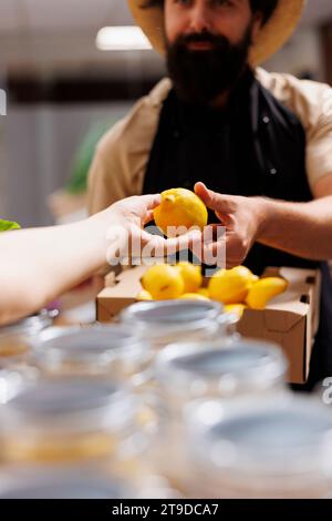 Il cliente del negozio zero rifiuti parla con il negoziante, chiedendo informazioni su un lotto di frutta biologica appena ricevuto. Cliente ecocompatibile in un negozio ecologico che chiede prodotti naturali Foto Stock