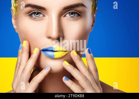 Donna sicura con rossetto giallo blu e bandiera Ucraina sullo sfondo Foto Stock