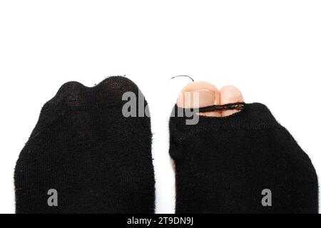 Primo piano di piedi maschili in vecchie calze di lana con le dita dei piedi che sporgono su sfondo bianco. Concetto di povertà e crisi finanziaria. Foto Stock