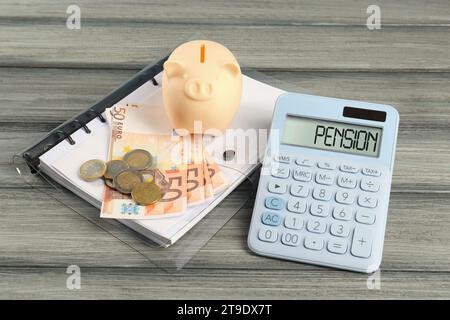Calcolatrice, salvadanaio, banconote in euro, monete e cartellino su tavolo di legno. Pianificazione pensionistica Foto Stock