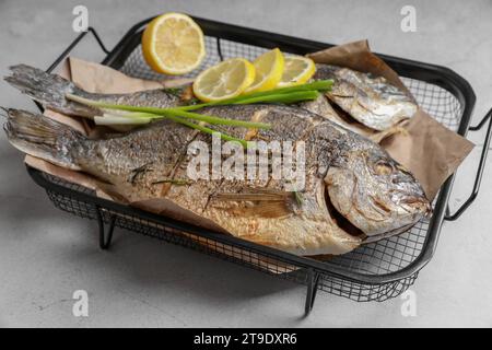 Frutti di mare. Delizioso pesce al forno servito con cipolla verde e limone su un tavolo dalla consistenza leggera, primo piano Foto Stock