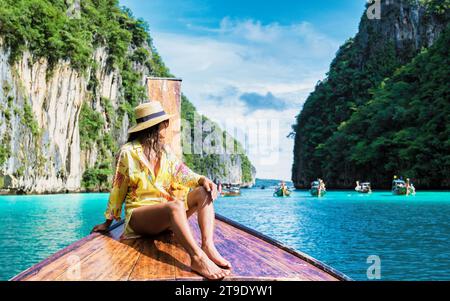 Donne asiatiche di fronte a una barca a coda lunga a Kho Phi Phi Tailandia, donne di fronte a una barca alla Laguna di Pileh con l'oceano colorato di turchouse durante un viaggio alla Baia Maya Foto Stock