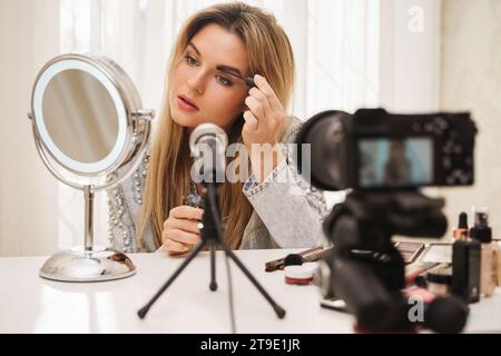 Giovane blogger di bellezza che utilizza gel di tinta sopracciglia durante la registrazione video per i suoi seguaci Foto Stock