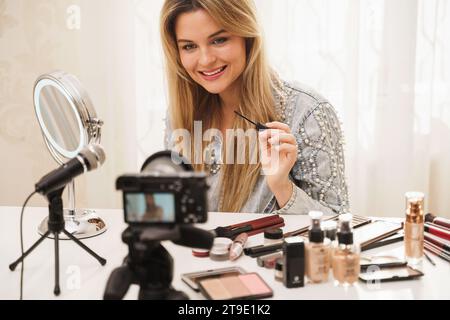 Giovane blogger di bellezza che utilizza gel di tinta sopracciglia durante la registrazione video per i suoi seguaci Foto Stock