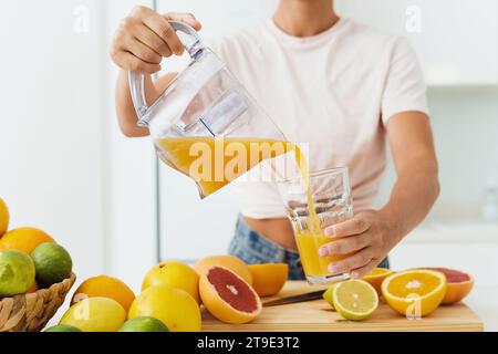 Primo piano di una donna che versa nel bicchiere del succo d'arancia appena spremuto Foto Stock