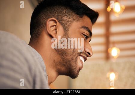 Uomo, faccia e felice di pensare o primo piano per idee, mentalità positiva e ispirazione in caffetteria. Indiano, sorriso e premuroso nel ristorante Foto Stock