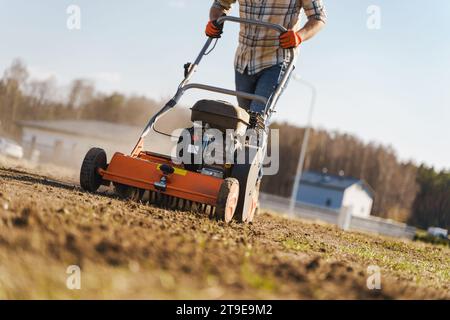 Giovane che utilizza una macchina per aerazione per scarificare e aerare prati o prati Foto Stock