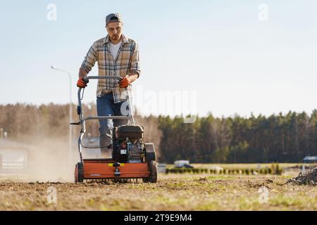 Giovane che utilizza una macchina per aerazione per scarificare e aerare prati o prati Foto Stock