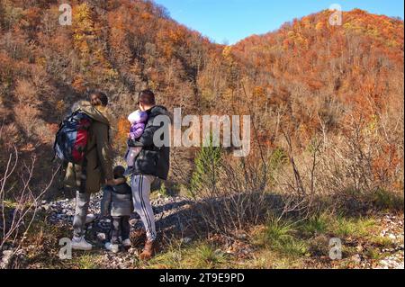 Famiglia giovane con bambini e bambini piccoli che camminano nel bosco Foto Stock