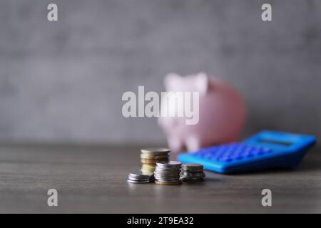 Immagine di messa a fuoco selettiva di monete, calcolatrice e salvadanaio con spazio di copia per il testo. Concetto finanziario. Foto Stock