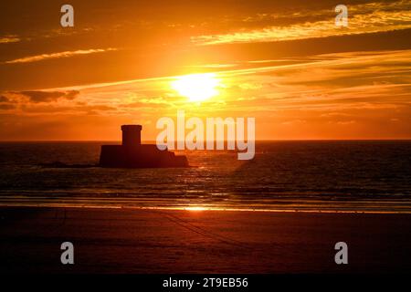 Silhouette della Torre la Rocco. Tramonto dinamico a St Ouen's Bay con la bassa marea. Jersey, Isole del Canale. Foto Stock