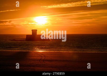 Silhouette della Torre la Rocco. Tramonto dinamico a St Ouen's Bay con la bassa marea. Jersey, Isole del Canale. Foto Stock