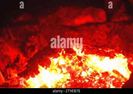 Primo piano del fuoco da campeggio che brucia e irradia calore durante la notte. Foto Stock