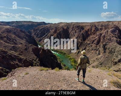 Turista sul bordo di una scogliera che si affaccia sul Charyn Canyon, la regione di Almaty, Kazakistan Foto Stock