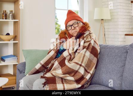 Ritratto di un uomo anziano che cerca di tenersi al caldo sotto una coperta a casa. Foto Stock