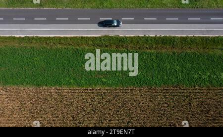 Vista droni di una strada di campagna con un'auto tra i campi di raccolta, Hofkirchen im Traunkreis, alta Austria, Austria Foto Stock