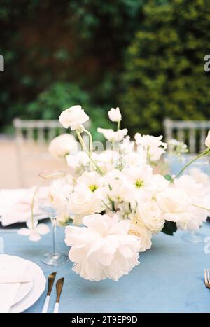 Bouquet di fiori si erge su un tavolo festivo vicino a un bicchiere Foto Stock