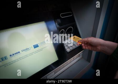 Atene, Grecia - 14.06.2023: Donna usa un bancomat greco per prelevare denaro. Uso editoriale. Foto Stock
