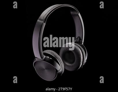 Un paio di cuffie nere su sfondo nero con spazio per la copia Foto Stock