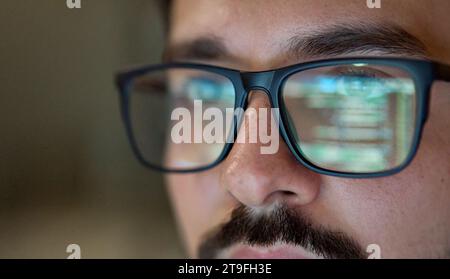 Uomo d'affari che indossa occhiali con riflesso usando il codice di sviluppo del computer. Foto Stock