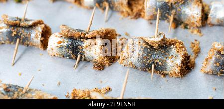 Sardine arrotolate al forno con condimento di pinoli, pangrattato, uva passa, sale e pepe. Cucina tipica siciliana. Buon cibo a base di pesce Foto Stock