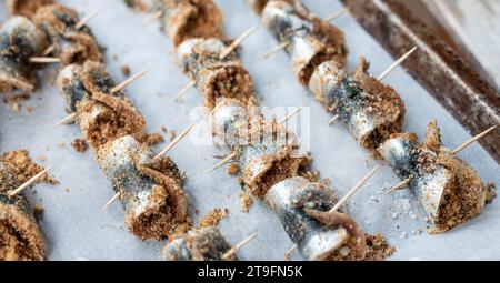 Sardine arrotolate al forno con condimento di pinoli, pangrattato, uva passa, sale e pepe. Cucina tipica siciliana. Buon cibo a base di pesce Foto Stock