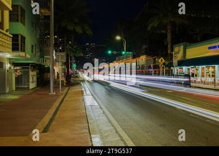 Scena notturna su Miami Beach con paesaggio urbano lungo Collins Avenue con tracciatori di luce sfocati provenienti dalle auto di passaggio. Foto Stock