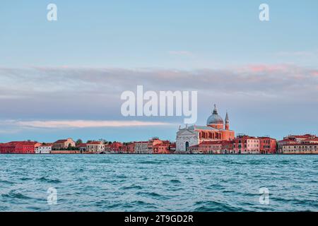 Venezia, Italia - 9 novembre 2023: Uno splendido scatto del Redentore e della Cattedrale del Santissimo sull'acqua al tramonto Foto Stock