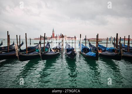 Venezia, Italia - 9 novembre 2023: Gondole tradizionali con il campanile della chiesa di San Giorgio maggiore sullo sfondo (vista da San Marco) Foto Stock