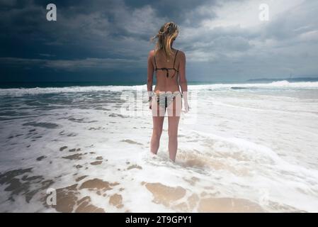 Una donna in bikini si trova sulla riva del mare sulla spiaggia di Tangalle, in Sri Lanka, in un giorno di nuvoloso Foto Stock