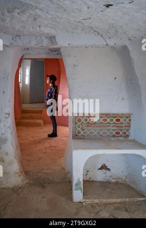 Donna all'interno di Argueda ha abbandonato le grotte che guardano attraverso la finestra con pareti rosa e bianche, in Spagna Foto Stock