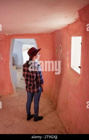 Donna che guarda la finestra all'interno delle grotte di Argueda con pareti rosa, in Spagna Foto Stock