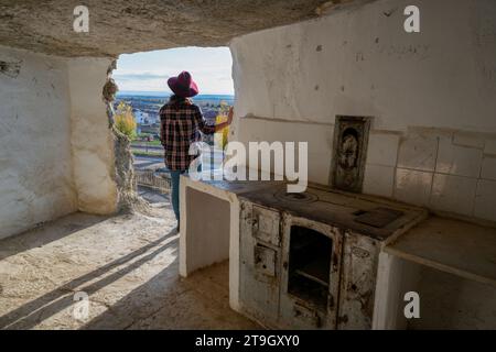 Donna che guarda la finestra all'interno delle grotte di Argueda con pareti bianche, in Spagna Foto Stock