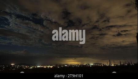 La città di Tucson si illumina da un promontorio che si affaccia sul deserto di notte. Guarda da vicino e vedrai la cometa NEOWISE nel cielo limpido. Foto Stock