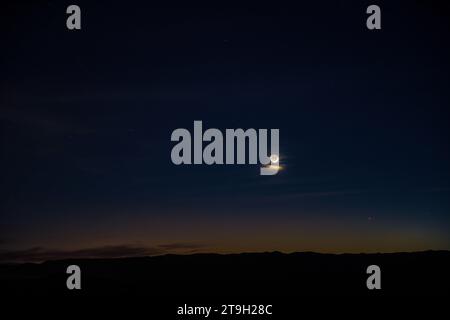 La luna mezzaluna con lucentezza di terra condivide il cielo occidentale con mercurio e Venere nel cielo del deserto riccamente colorato al crepuscolo. Foto Stock