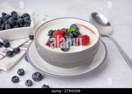 Ciotola di gustoso porridge di semola con frutti di bosco freschi su sfondo bianco Foto Stock