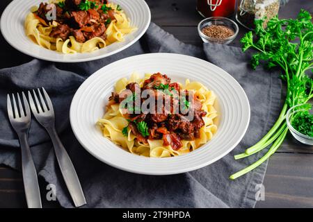 Goulash tedesco servito su tagliatelle di uova in bocce poco profonde: Pezzi di manzo bolliti conditi con marjoram, semi di carvi e paprika Foto Stock