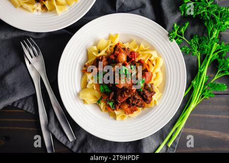 Goulash tedesco servito su tagliatelle di uova in una ciotola poco profonda: Pezzi di manzo bolliti conditi con marjoram, semi di carvi e paprika Foto Stock