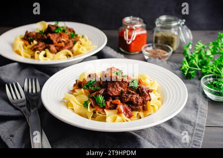 Goulash tedesco servito su tagliatelle di uova in bocce poco profonde: Pezzi di manzo bolliti conditi con marjoram, semi di carvi e paprika Foto Stock